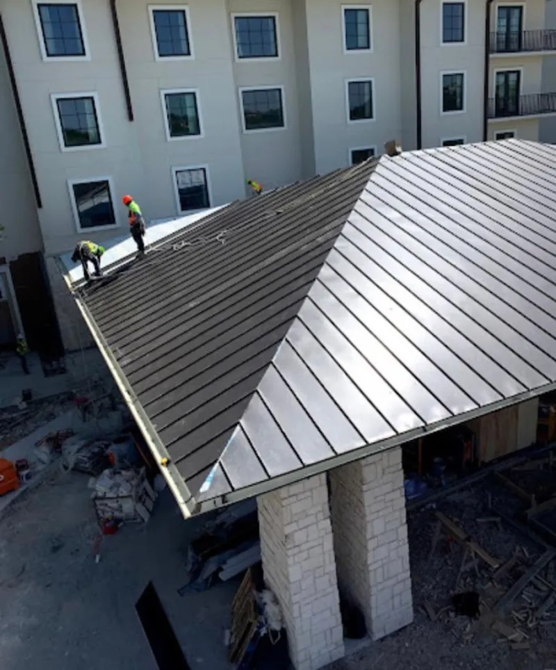 Crew installing standing seam metal roof panels on a commercial project in Milledgeville